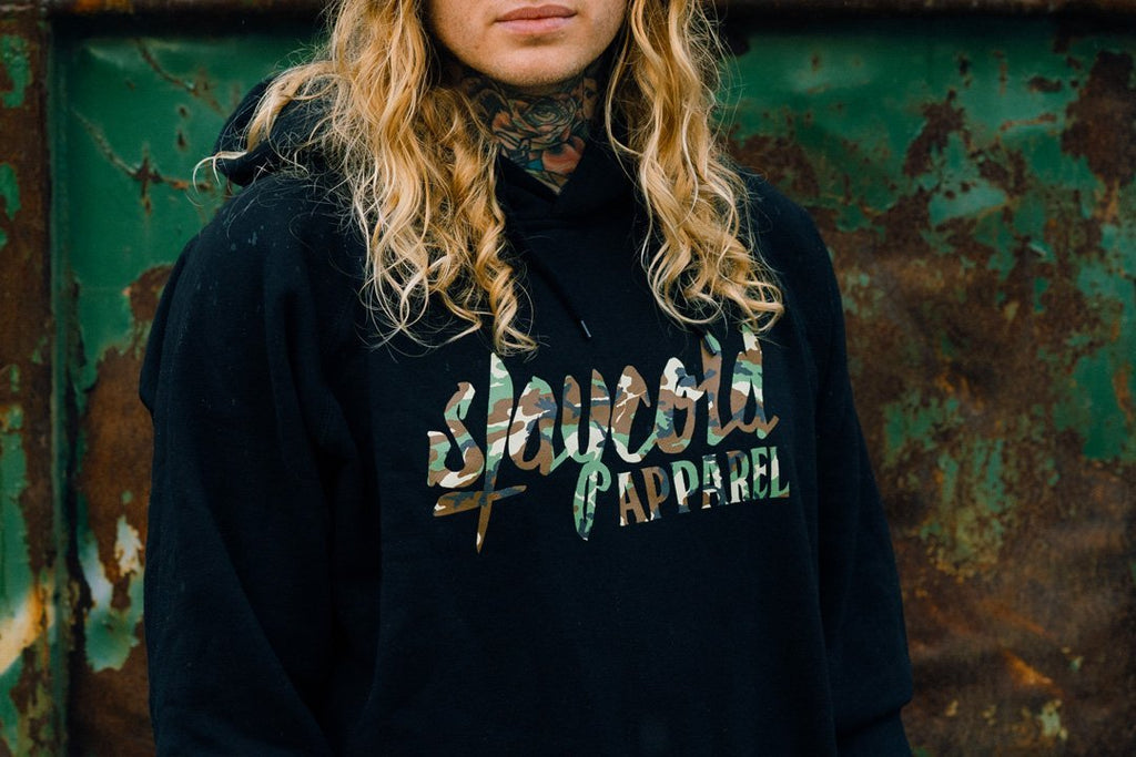 Male tattooed Model wearing the new Stay Cold Apparel Variation of the Essential Logo Hoodie in Camouflage Woodland