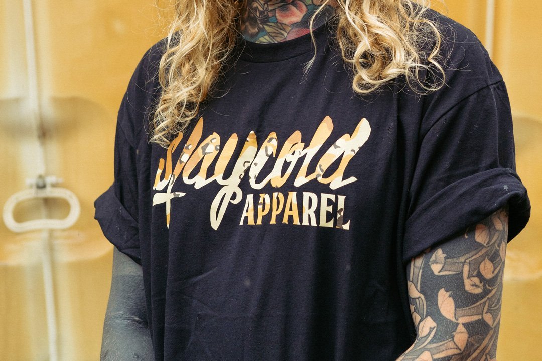 Male Tattooed Model wearing the new Stay Cold Apparel Variation of the Essential Logo Tee in Camouflage Sand