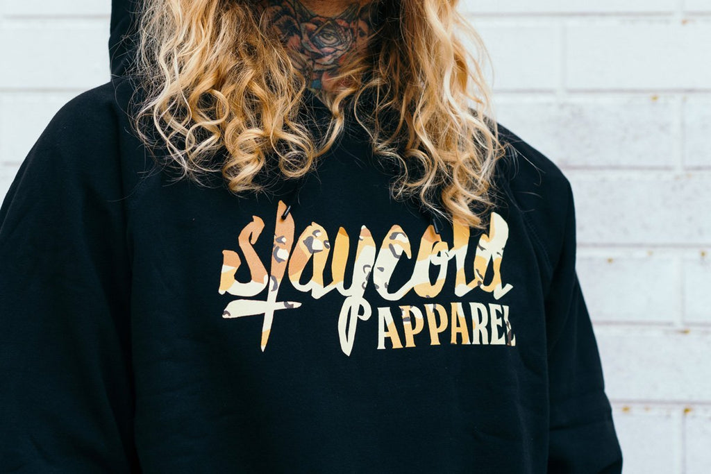 Male tattooed Model in sunglasses wearing the new Stay Cold Apparel Variation of the Essential Logo Hoodie in Camouflage Desert Storm